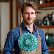 Portrait of glass artist Ben Carter holding an intricate glass sculpture.