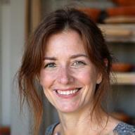 Portrait of ceramicist Clara Evans in her studio, smiling confidently.